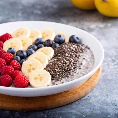 A vibrant healthy breakfast plate with a smoothie bowl topped with chia seeds, fresh berries, sliced bananas, and a sprinkle of granola clipart