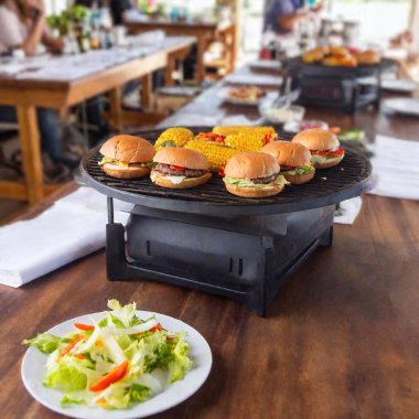 Extreme Wide Shot of a Summer Cookout with Hamburgers and Sides: A soft focus photo showing a summer cookout with hamburgers and side dishes on tables at eye level. clipart