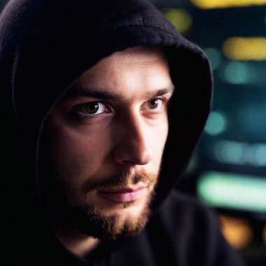 A close-up, eye-level portrait of a male hacker, with his eyes reflecting the glow of the computer screen in sharp focus, while the background softly blurs into darkness, capturing the intensity of the digital battle clipart