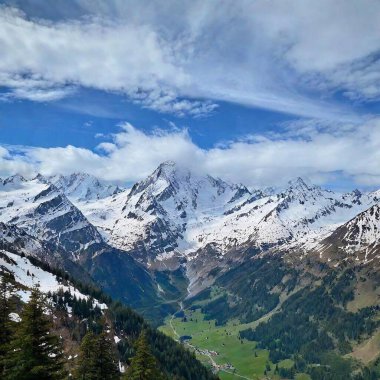 A full shot of a mountain range at eye level, with snow-capped peaks and a lush valley below, eagle in sky clipart