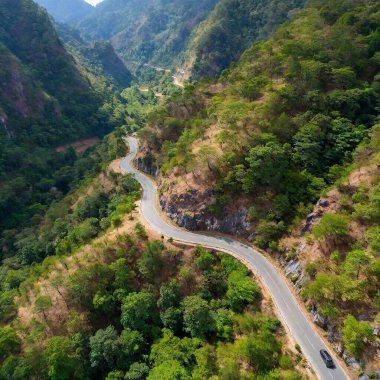 A full shot bird's-eye view of a steep mountain pass, with deep focus highlighting the winding road cutting through the rocky terrain. clipart