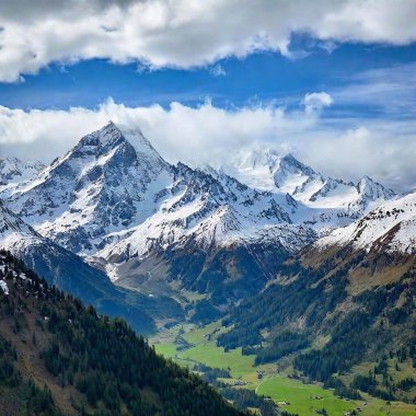 A full shot of a mountain range with eagle in sky at eye level, with snow-capped peaks and a lush valley below clipart