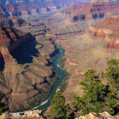 A full shot birds-eye-view photo of canyon scenery, with soft focus highlighting the winding river at the bottom of the canyon and the layered rock formations. clipart