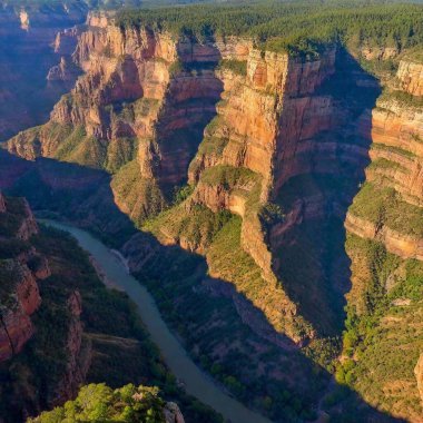 A full shot birds-eye-view photo of a dramatic canyon scenery, capturing the sheer cliffs and winding paths with a soft focus that emphasizes the grandeur and scale of the landscape. clipart