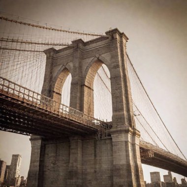 A high-resolution photograph captures the iconic structure of the Brooklyn Bridge from a low angle, highlighting its intricate cables and Gothic-style towers. The composition masterfully frames the New York City skyline in the background clipart