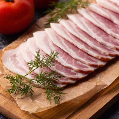 A high-resolution ultrarealistic image showcases thinly sliced bacon artfully arranged on a round wooden cutting board. The bacon, with its marbled layers of pink meat and white fat, is stacked in a neat, fan-like formation. A small, fresh sprig of clipart