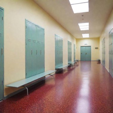 A high-resolution ultrarealistic image of a long, empty school hallway with the walls and floors covered in a pale cream color. This photograph features rows of teal lockers with silver locks lining both sides of the corridor. Above, fluorescent clipart