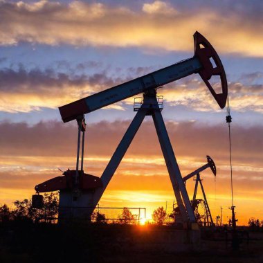 A high-resolution ultrarealistic image of oil pump jacks silhouetted against a vibrant, colorful sunset sky. The digital photograph captures the dark silhouettes of the industrial machines, highlighting their intricate mechanical structures. The clipart