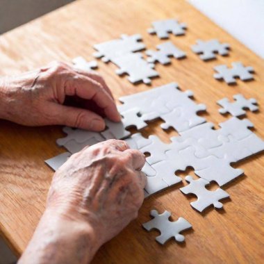 A high-resolution ultrarealistic image captures a close-up scene of an elderly person's hands assembling a jigsaw puzzle in the shape of a human head. The digital photograph showcases the fine details of wrinkled hands, highlighting the contrast clipart