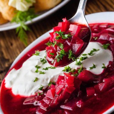 Extreme macro, eye-level shot of a spoonful of Ukrainian borscht, with vibrant red beet soup, a swirl of sour cream, and fresh dill garnish in sharp focus, fading into soft detail around the edges in a photo-realistic style using rack focus clipart