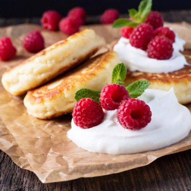 Extreme macro shot of the creamy texture of Ukrainian syrnyky (cottage cheese pancakes), with a dollop of sour cream and fresh berries in sharp focus at eye level, using rack focus to create depth in a photo-realistic setting clipart