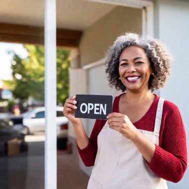 A candid shot of an older multiracial female business owner in her late 50s, standing outside her small business storefront, holding an 