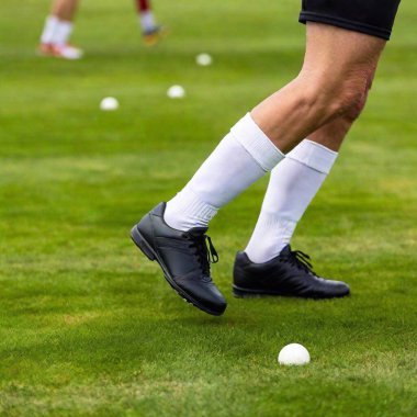 Senior male player cleats just as they hit the grass, with deep focus capturing the blades of grass and nearby players. clipart