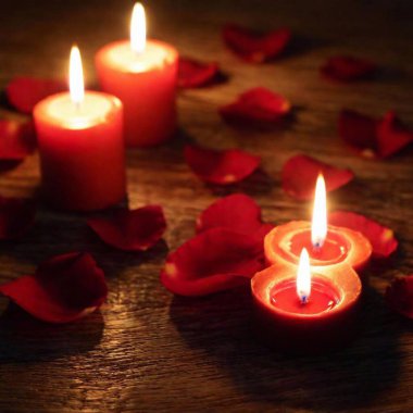 Close-up view of candles and fresh red rose petals on polished wooden surface. Valentines day clipart