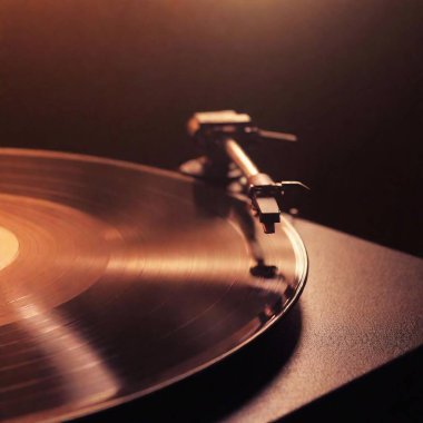 extreme close-up of a vinyl record spinning on a turntable with the needle positioned on the grooves. The warm lighting highlights the texture and shine of the record  clipart