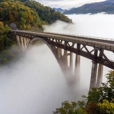 A full shot of a decayed, old bridge extending into thick fog, with the chasm below disappearing into darkness. The soft focus enhances the sense of danger and the unknown clipart