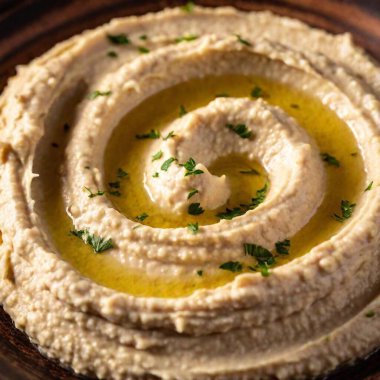 Close-up of smooth, creamy hummus with a swirl of olive oil. clipart