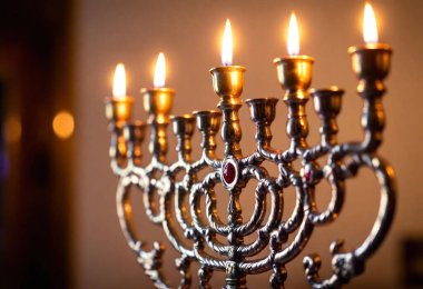 A macro shot of the glossy silver metal details on an ornate menorah, with the gleaming flame of each candle reflecting off the surface. clipart