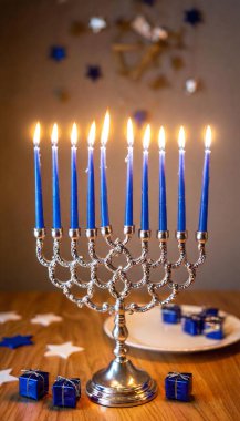 A close-up of blue and silver Hanukkah decorations around a glowing menorah, with glittering stars of David hanging from the ceiling. clipart