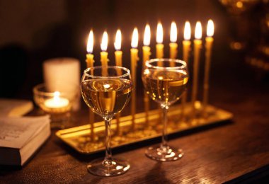 A high-angle shot of two glasses of wine beside a golden menorah, with candles burning brightly in the cozy light. clipart