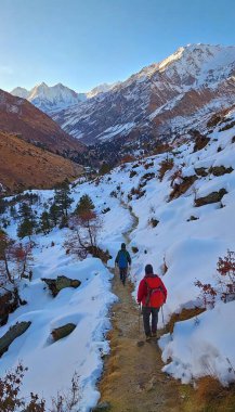 Trekking Through the Himalayas: An awe-inspiring scene featuring a daring trek through the Himalayas. Snow-covered peaks tower in the distance while a group of adventurers in colorful gear ascends a rugged path, surrounded by spectacular views of clipart