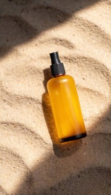 A glass sunscreen bottle with colorful summer patterns, placed on a glowing sand-textured surface. clipart