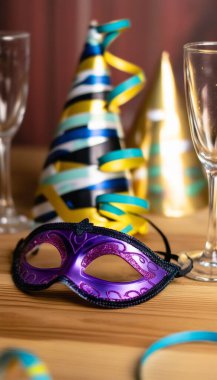 Extreme close up of a party mask with glitter, placed on a table next to sparkling champagne flutes clipart