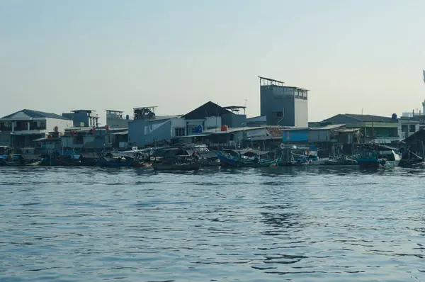 Sunda Kelapa Limanı 'nda mavi gökyüzü ve kalabalık evleri olan birçok tekne var.