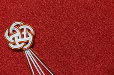 Kırmızı zemin üzerinde Japon düğümü süslemesi.  