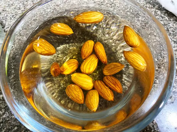 stock image transparent bowl filled with water, a handful of almonds are soaking, creating a serene and visually appealing scene.