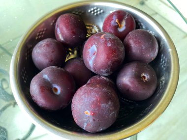 Bir kâseye yerleştirilmiş olgun eriklerin yakın çekimi, derin mor derilerini ve canlı iç organlarını gözler önüne seriyor..