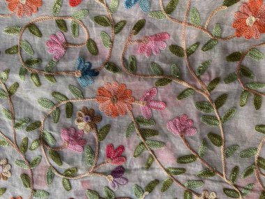 Yumuşak beyaz pamuk kumaşı süsleyen renkli, canlı, renkli bir çelenk kaş işlemesi..