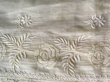 Karmaşık beyaz bir Chikankari çiçek deseni zarif bir şekilde yumuşak beyaz kumaşa işlenir..