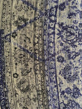 Karmaşık bir Arap geometrik izi, birbirine kenetlenmiş şekillerin ve hassas motiflerin simetrik desenlerini içeren yumuşak soluk mavi-gri kumaşı süsler..