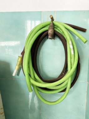 Sarılmış yeşil ve kahverengi borular, metalik bir musluğun etrafına güzelce katlanır.