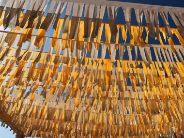 Beyaz ve sarı banderita şeritleri rüzgarda zarif bir şekilde çırpınıyor., 