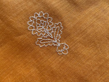 Çiçek tasarımının beyaz iplik işlemeli dış görünüşünü kapat 