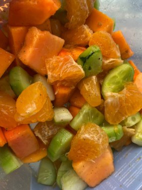 Taze kesilmiş papaya, elma ve salatalık yakın plan, farklı dokuları, canlı renkleri ve sulu tazeliği sergileniyor.