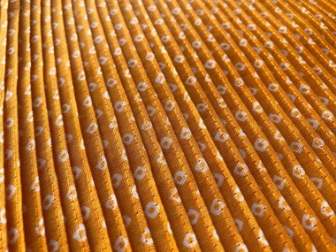 close-up view of intricate white bandhani block prints adorning mustard silk fabric, enhanced by delicate pleating. clipart