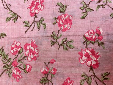 Pembe ve beyaz manastır işlemeli çiçek deseni zarif pembe ham ipek kumaşa dikili, zarafet ve işçiliğin kusursuz bir karışımını oluşturuyor.