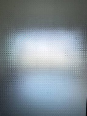 Bulanık cam bir yüzey, ince buzlu bir dokuyla süslenmiş, güneş ışığını yumuşak ve sessiz ışınlara dağıtıyor..