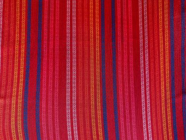 Vertical red, yellow, white, and blue woven lines adorn the red georgette fabric, forming a bold and vibrant pattern. clipart