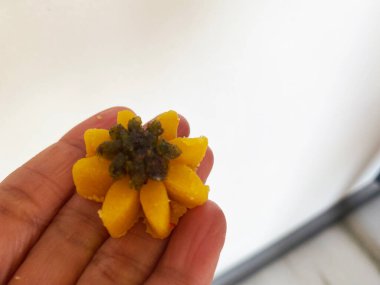 Narin bir Hint tatlısı, güzel bir çiçek şekline bürünmüş, nazikçe avucunun içinde duruyor, karmaşık tasarımını sergiliyor.. 