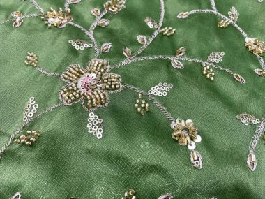 Elle işlenmiş çiçek çeliği yeşil dokuları süslüyor, tiki ve kardana süslemeleriyle parıldıyor.. 