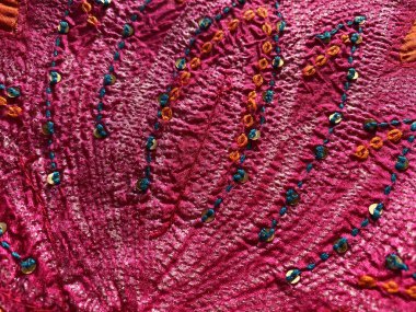  Yakın plan görüntüler, canlı pembe kumaş üzerine karmaşık el nakışları sergiliyor, zengin dokuyu ekleyen yeşil tikki işleriyle süslenmiş.. 