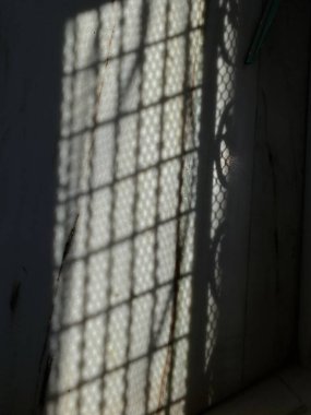 Güneş ışığı ızgaranın içinden süzülüyor, mermer boyunca sessiz bir şiir gibi ince ışık demetleri oluşturuyor..