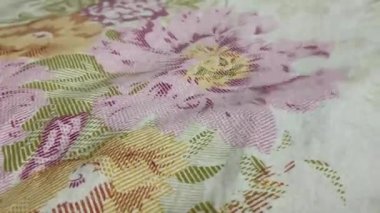 Baskılı çiçek kumaşı rüzgarda çırpınıyor. Renkli desenleri, hava hareket ettikçe zarifçe değişiyor. Yaşam ve enerji dolu yumuşak ve dinamik bir hareket yaratıyor..