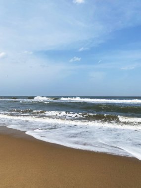 Yumuşak dalgalar süzülür ve güneşli altın bir kıyı şeridinde kırılır. Sıcak kumun üzerine beyaz köpük yayılır. Durgun ve sonsuz bir hareketle..