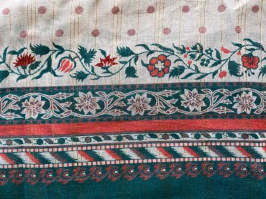 Yeşil ve turuncu renkte karmaşık bir geometrik kenar yumuşak pembe pamuk kumaşa zarif bir şekilde basılmıştır..