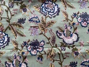 Zarif mavi bir Babür çiçek deseniyle süslenmiş, koyu yeşil pamuklu kumaş. Karmaşık motiflerini vurguluyor..